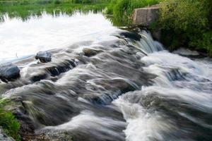 una pequeña cascada de río en un brillante día soleado de verano. foto