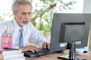 Asian elderly businessman working on computers photo