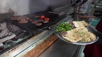 polpette di carne alla griglia. polpette al forno su carbone. il maestro porta le polpette sul piatto da portata con una pinza. video