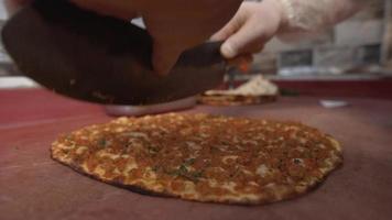 The cook slices and cuts the pita. The cook cuts the pita into four pieces with a knife. video
