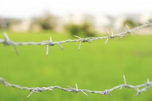 valla de alambre de púas con fondo borroso en el campo. foto