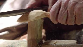 Making wooden spoons by processing wood. The hands of the master who makes wooden spoons are processing the wood.