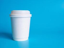 Front top view, disposable white coffee paper cup white with hot black coffee americano, no sugar milk, ready to drink, refreshing. aroma awake fresh to work placed on  Blue isolated background photo