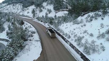 Truck driving on asphalt road in winter, logistics. Truck driving on asphalt road among snowy forests.