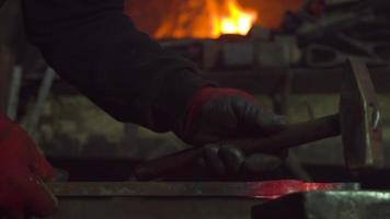 Blacksmith, old-fashioned ironworking. The master is forging the hot iron. Burning fire. video