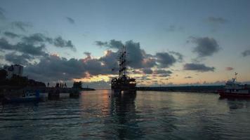 Hafen bei Sonnenuntergang. historisch aussehendes Schiff. Das große Schiff verlässt den Hafen. video