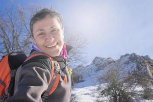 retrato de una mujer sonriente excursionista en una montaña cubierta de nieve foto