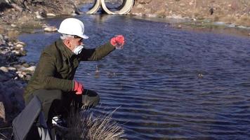 Análisis de aguas sucias de río. el perito, que toma una muestra del río, examina el agua y toma notas en la tablilla. hace análisis tecnológicos y científicos del agua. video