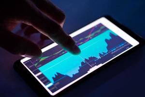 gráfico de indicadores táctiles de hombre del mercado de valores en el teléfono inteligente foto