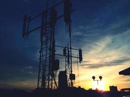 Blurred silhouette of communication, television digital TV or broadcasting tower with sunset light, cloud and sky background at twilight time. Technology and Beauty in nature concept photo