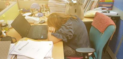 Bangkok, Thailand-October 2, 2018 Asian woman staff sitting and sleeping on wooden table during work near black notebook, bag with orange light and document background at office. Lazy employee concept photo