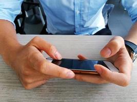 Close up hand of young business man holding smart phone. He is playing game, chatting, using internet and connecting wireless network on mobile phone photo