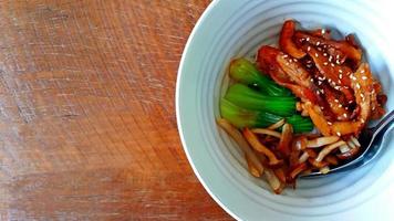 Close up and Top view Chicken teriyaki with rice in the white bowl on the wooden table and left blank space. photo