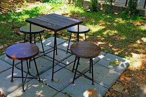 Set of wooden chairs and table at the garden with sun light and grass field. Vintage and classic table and chairs photo