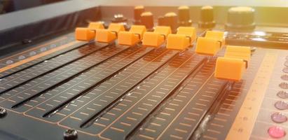 Blurred close up orange button of sound mixer panel equipment for mixing or control audio system with sunlight flare - Technology, Tool and Digital device concept photo