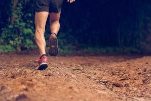 primer plano de hombre sendero corriendo en terreno rocoso. El primer plano de los pies masculinos atraviesa un terreno rocoso. centrarse en los zapatos. foto