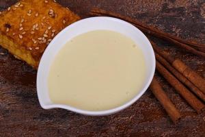 Condenced milk in the bowl with sinnamon and pastry photo