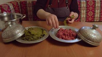 Sarma turc. repas turc. la femme qui met de la viande hachée entre les feuilles de vigne et enveloppe les feuilles. fabrication d'emballages de feuilles de nourriture turque. video