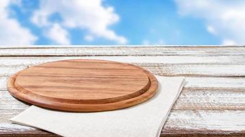 empty pizza board on empty wooden table with tablecloth,napkin - top view photo