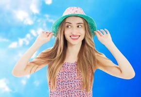 Close-up portrait of happy girl with mid-back length hair in summer hat. Outdoor photo of laughing romantic woman taking picture in summer morning.