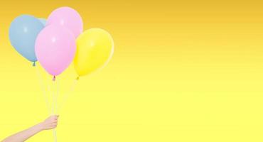 sujetar a mano globos de colores aislados en fondo amarillo, vacaciones y diversión foto