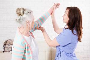 el fisioterapeuta está impartiendo una lección de rehabilitación con una anciana en casa o en una clínica. foto