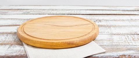 empty pizza board on empty wooden table with tablecloth,napkin - top view photo