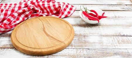 tablero vacío y pimiento rojo picante en una mesa vacía foto