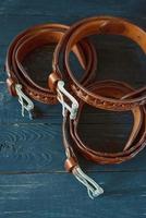 three leather brown belts on dark wooden background photo