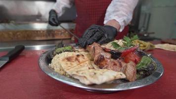 Putting the meat skewers on the serving plate. The chef puts the meat skewers on the serving plate. video