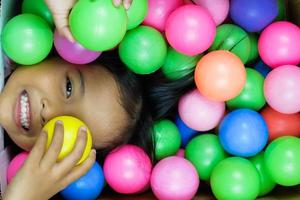 A girl smiling broadly playing in the colorful ball photo