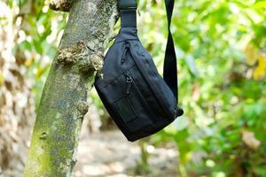 Men's black waist bag hanging on the tree photo