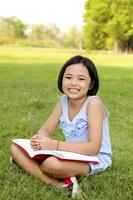 niña asiática leyendo un libro en el parque foto