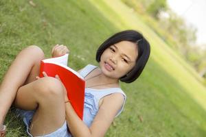 niña asiática leyendo un libro en el parque foto