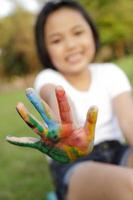 niña asiática con las manos pintadas en pinturas coloridas foto