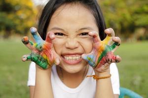 niña asiática con las manos pintadas en pinturas coloridas foto