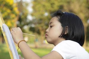 Asian little girl painting in in the park photo