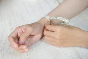 mano femenina midiendo la muñeca con una cinta métrica foto