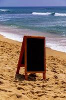 Chalk board for text, message or advertising on the sunny ocean beach photo