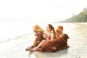 A young woman plays with her dogs on the beach. Healthy active lifestyle concept. Relaxation with a pet. photo