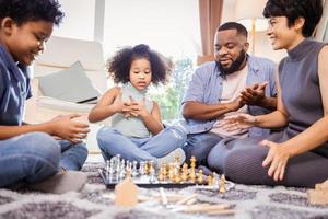 Happy African American family playing chess together in living room at home photo