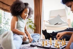 African American girl playing chess with the African American boy in the living room at home photo