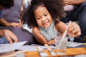 African American Little Girl drawing with watercolors in the living room at home photo