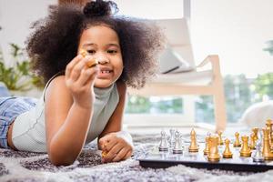 Smiling African American girl while playing chess on the floor in the living room at home photo