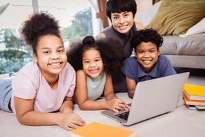 niños afroamericanos felices estudiando en línea por computadora portátil con madre en casa foto