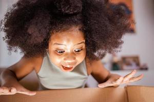 New house happy homeowners family. Surprised girl unpack big gift box at home photo