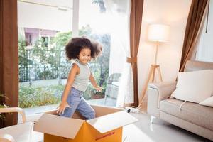 Happy African American little girl playing with a paper box - children play photo