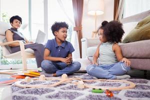 African American little kid boy and girl having fun while playing toys in the living room on floor photo