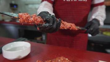 turkisk adana kebabmästare. kocken förbereder adana kebab. snöra kött på spett. köttspett. video