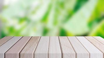 Copy space of blurry green banana leaf tree. Empty desk shelf brown wooden of front. photo